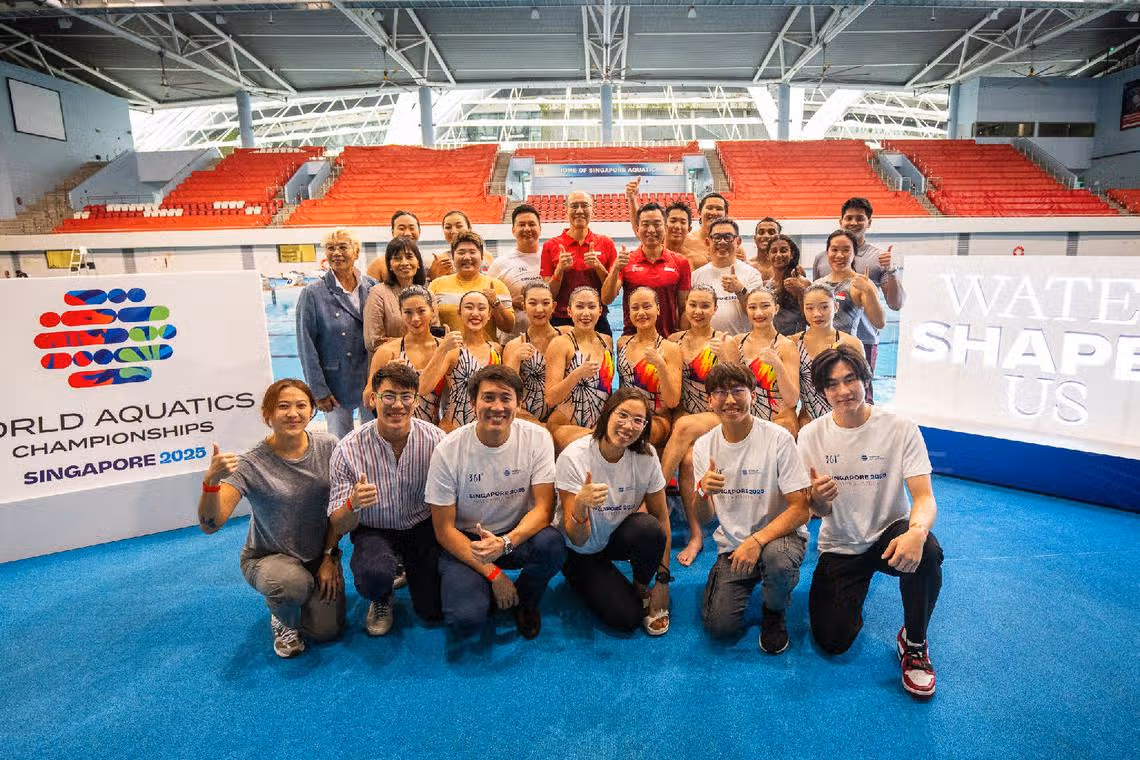 Group photo of athletes, coaches, and officials at the World Aquatics Championships Singapore 2025, featuring synchronized swimming team at OCBC Aquatic Centre.
