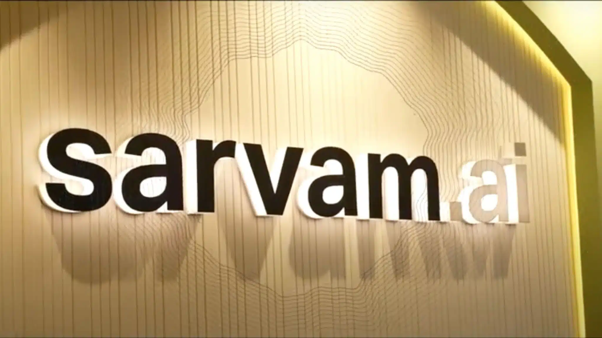 Sarvam.ai logo displayed on an office wall with modern backlighting and textured design, representing an emerging AI startup from India.